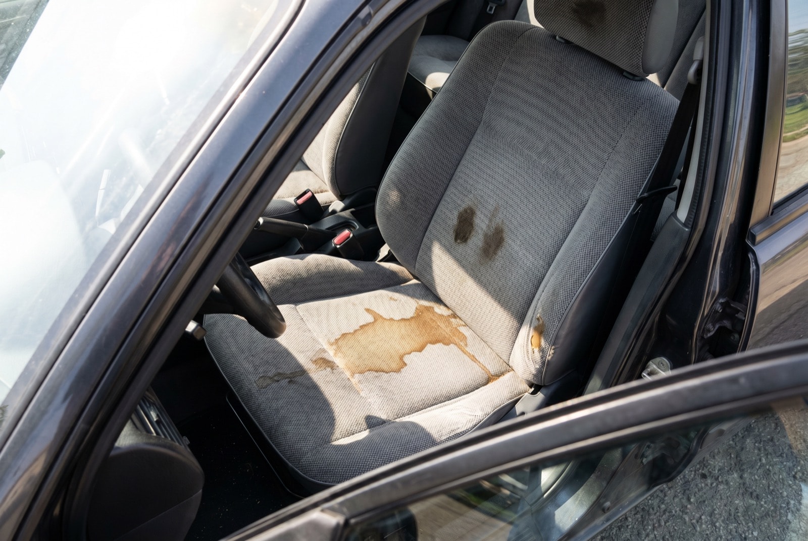 Stoff-Autositz mit Kaffeefleck und eingetretenem Schmutz – vor der Tiefenreinigung